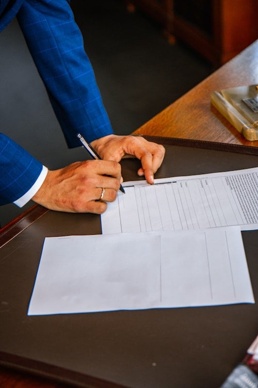 Businessman hands signing an inheritance advance loan document.